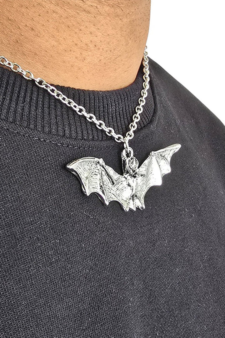 Silver bat pendant necklace on a person wearing a dark gray sweater.