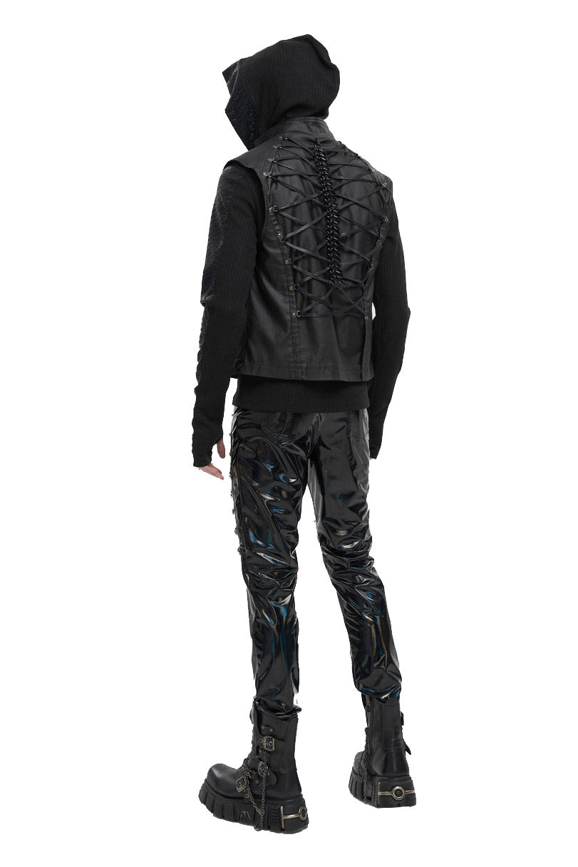 A man wearing a black sleeveless motorcycle vest with a high collar and black spine hardware, paired with matching black pants and boots.