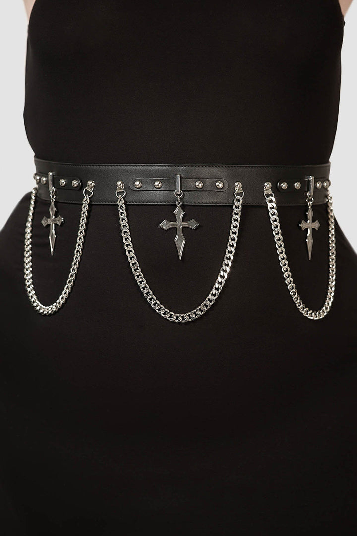 Black belt with chains and crosses worn by a person on a plain background