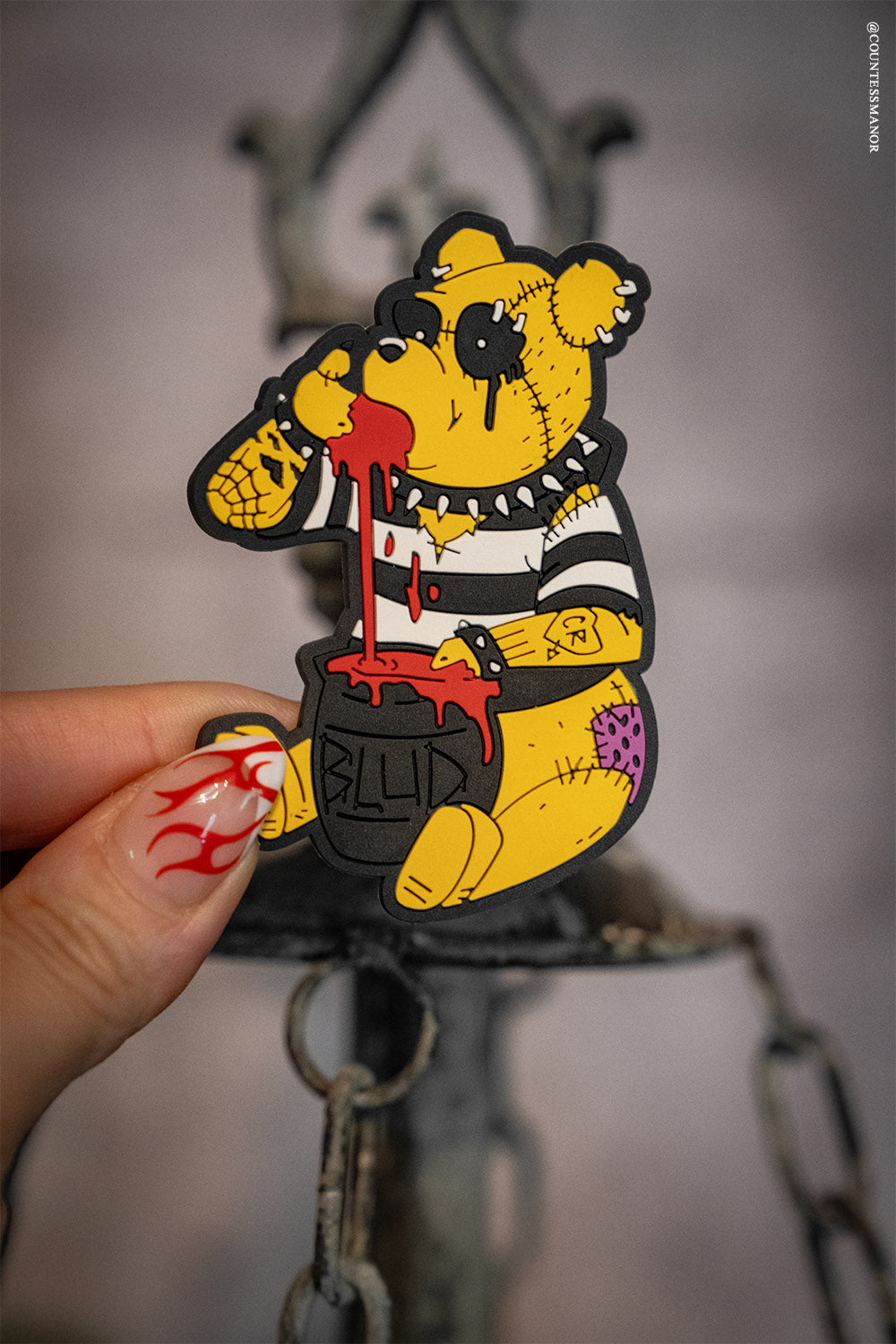 creepy cute bear magnet held by a tattooed hand with a blurred background