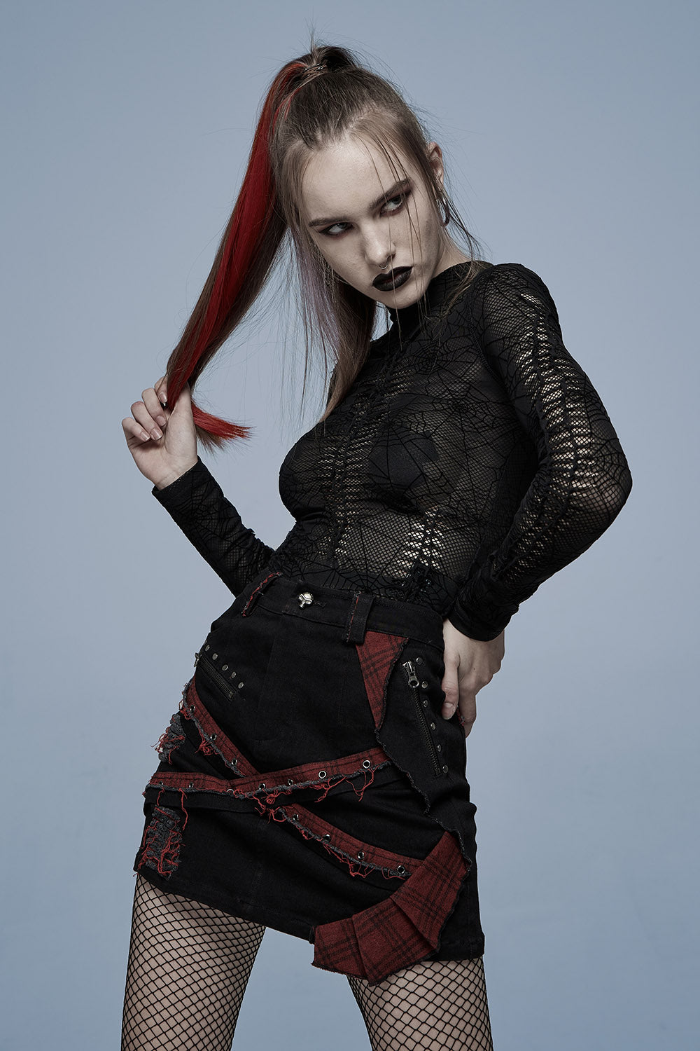 Woman in a black and red outfit against a gray background