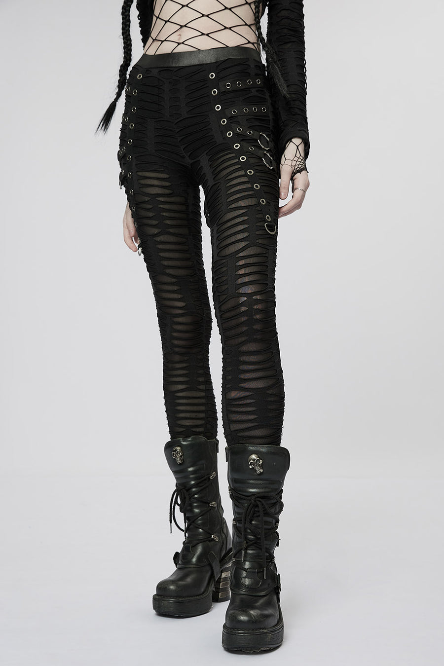 Person wearing black distressed leggings pants and boots on a white background