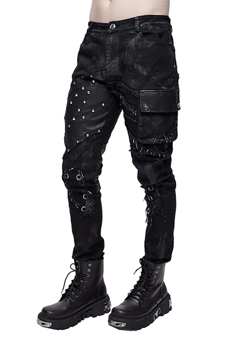 A pair of men's distressed punk pants with large metal eyelets and silver studs, featuring stitched details and aged accents. The pants are black and made with a vegan leather pocket.