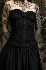 Black lace corset top worn by a person with tattoos against a natural background