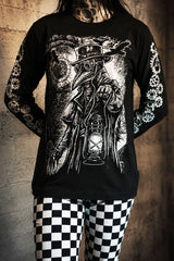 Person wearing a black long-sleeve shirt with a detailed graphic design of a steampunk character holding a lantern, standing against a textured wall.