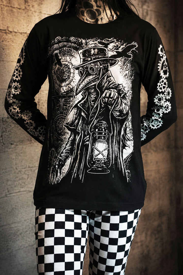 Person wearing a black long-sleeve shirt with a detailed graphic design of a steampunk character holding a lantern, standing against a textured wall.