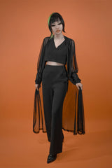 female model wearing Beyond the Veil Duster from Lively Ghosts over black top and black bottoms against orange background