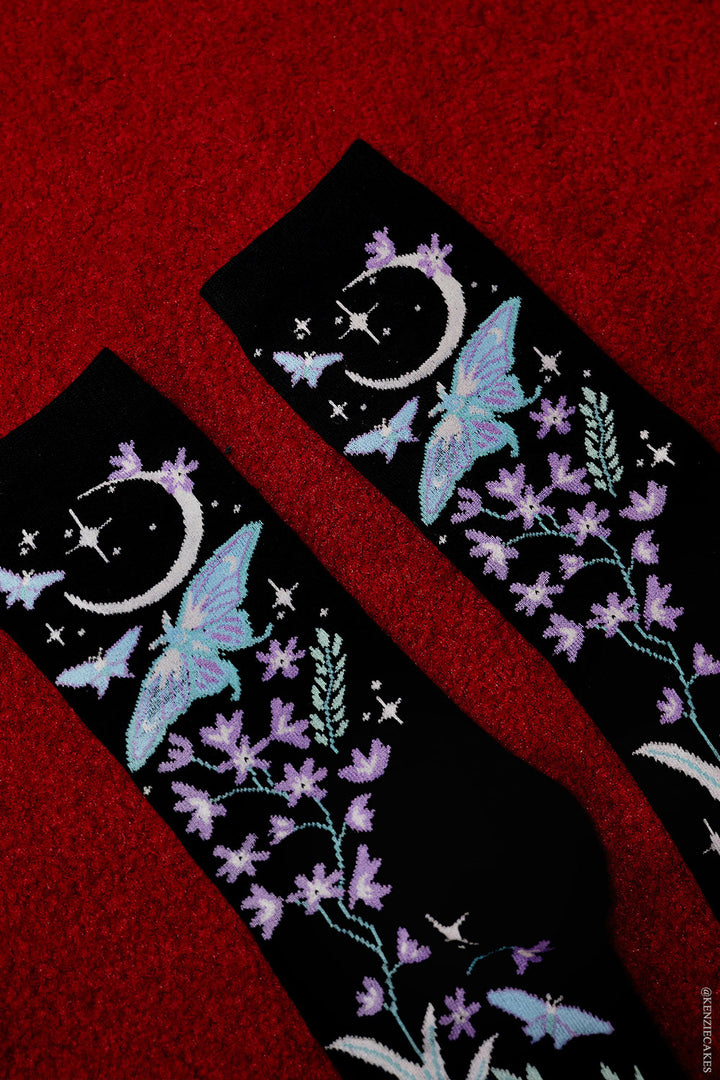 knitted socks featuring moons, moths, and flowers made of a cotton blend