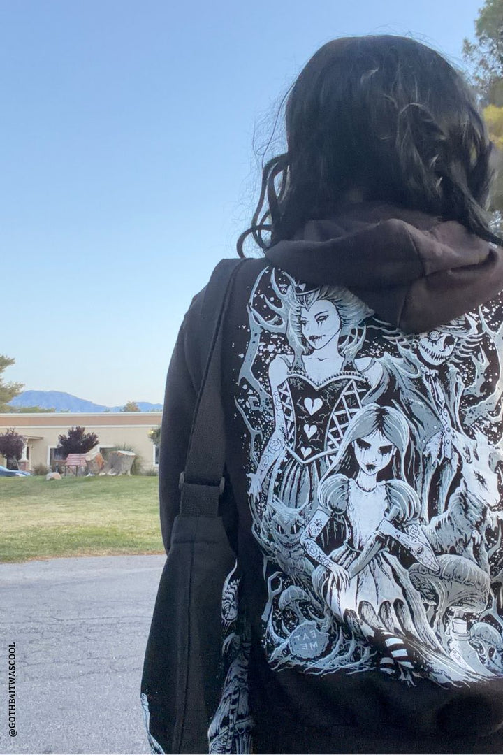 Person wearing a hoodie with a detailed design of a woman and birds outdoors.