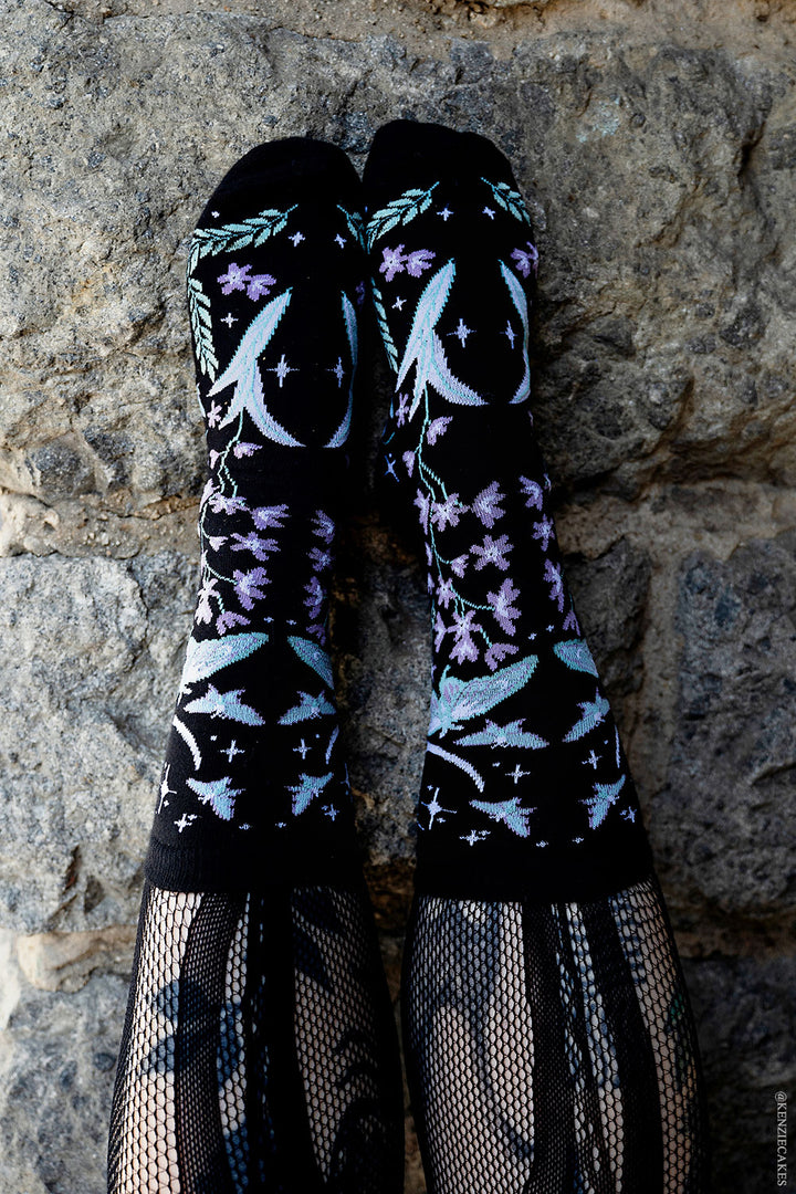 dark cottagecore knitted socks featuring moons, moths, and flowers