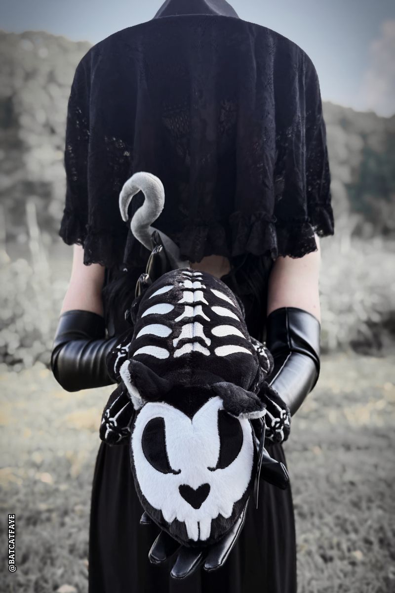 Gothic woman holding a skeleton rat plushie 