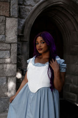 female model with purple hair wearing a light blue dress with a while corset