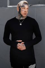 gothic man wearing a black long-sleeve shirt against a gray wall