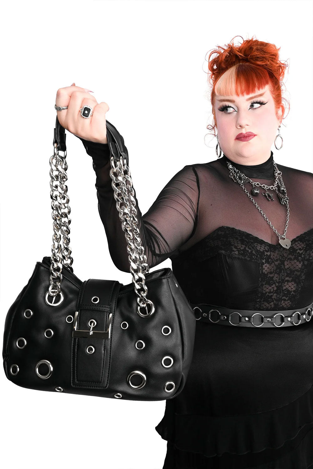 Gothic black grommet handbag styled with an alternative outfit, sheer black sleeves, and dark romantic punk fashion