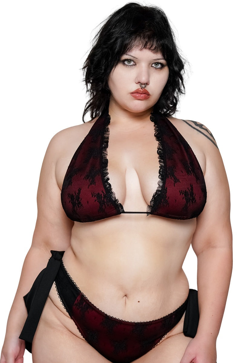 Woman wearing a red and black patterned bikini against a white background