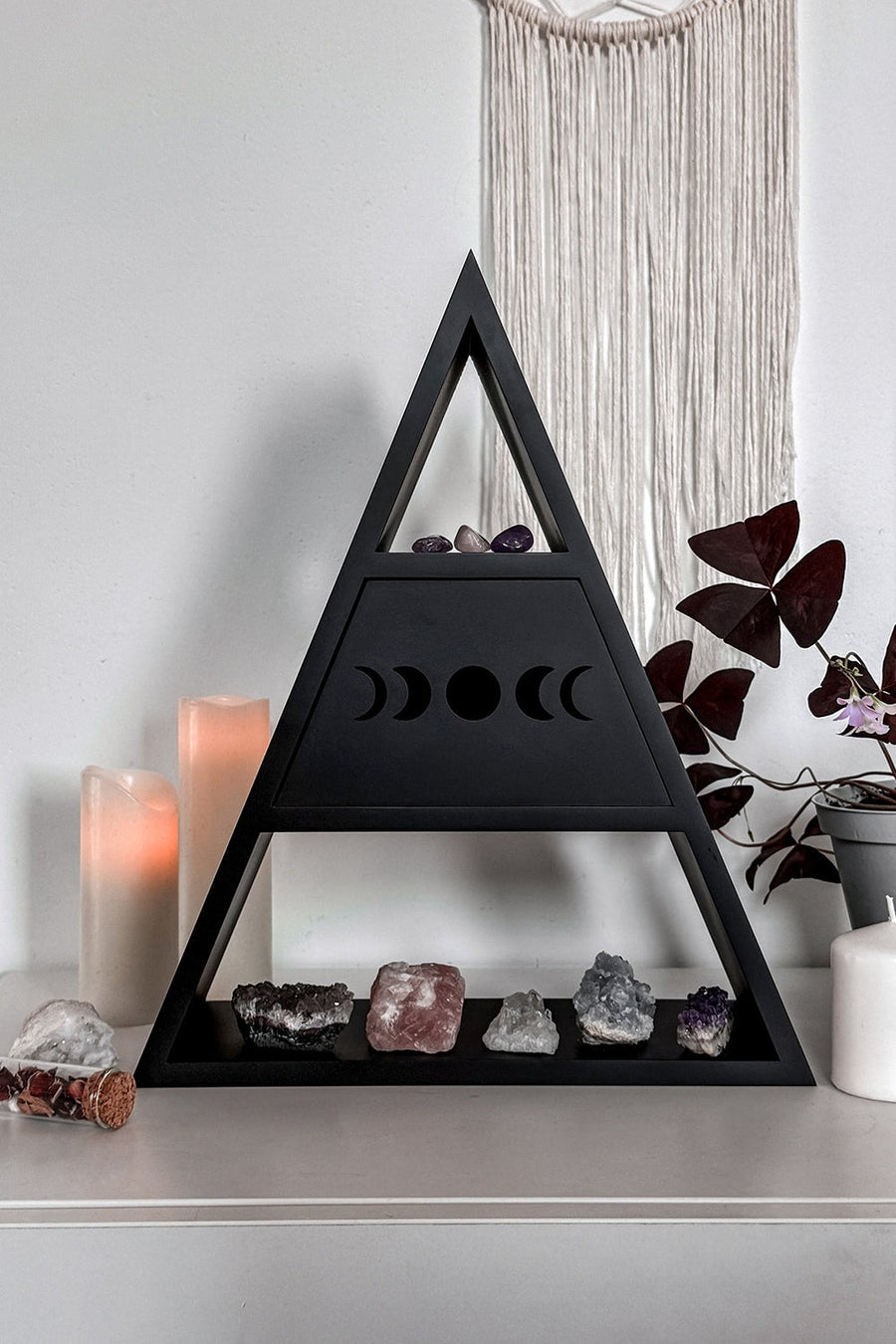 Black triangular crystal holder with crystals on a white surface