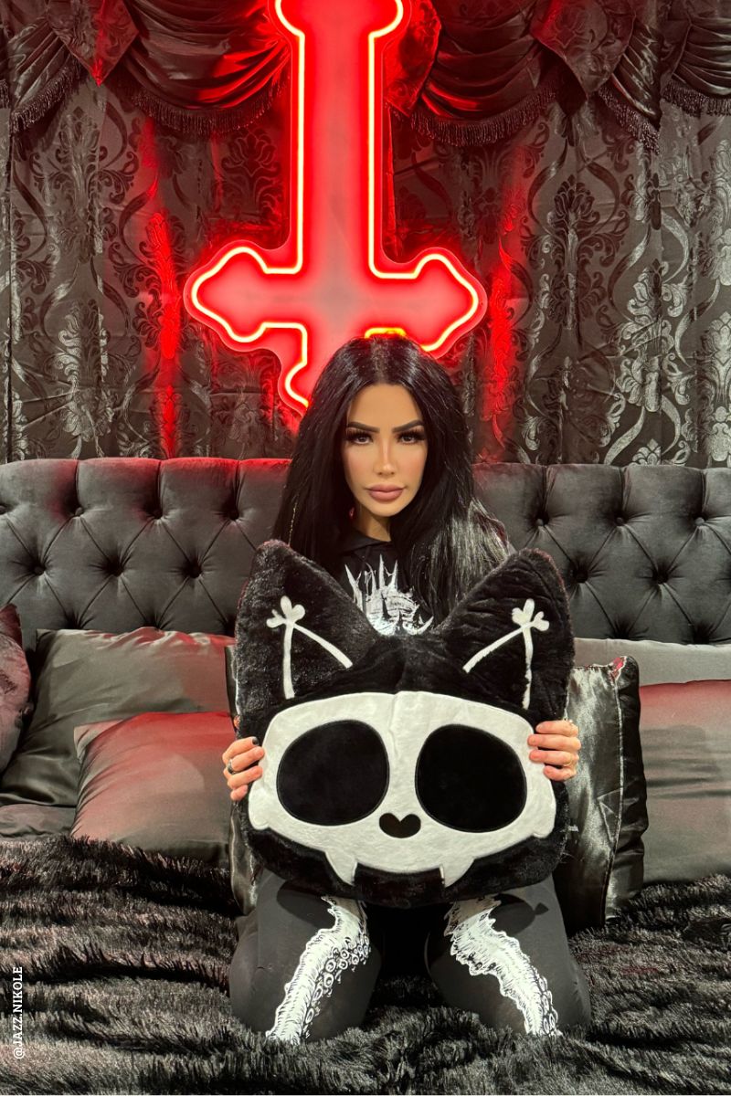 gothic woman holding a black throw cat pillow 