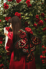 Model wearing red moth luna moth backpack surrounded by red roses