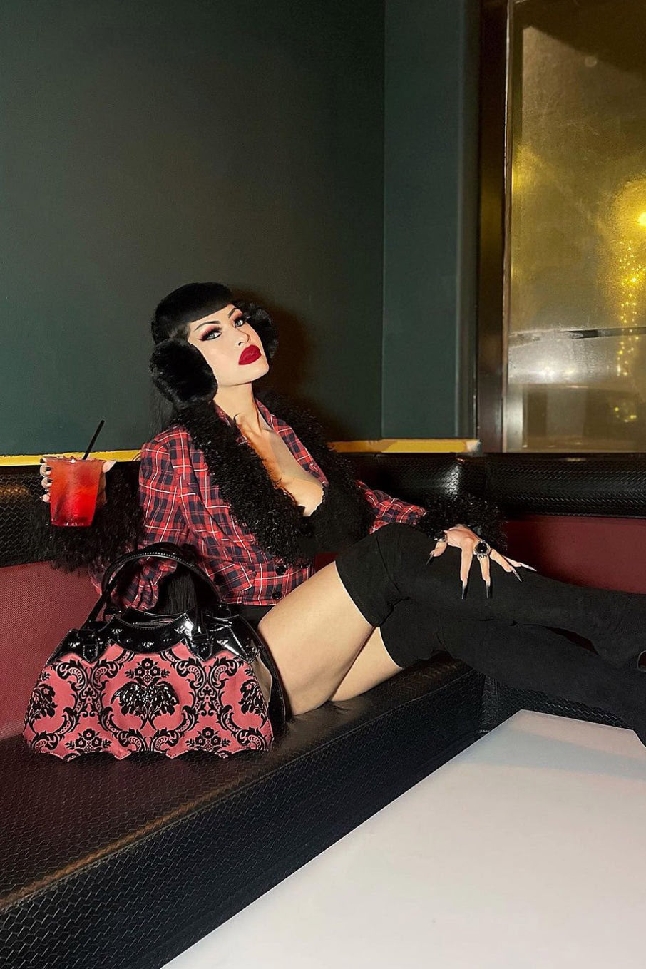 red and black gothic handbag posed beside a gothic woman