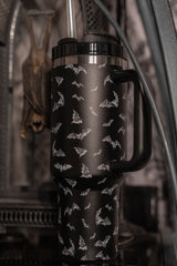Black thermos with bat pattern in a dark, possibly indoor setting