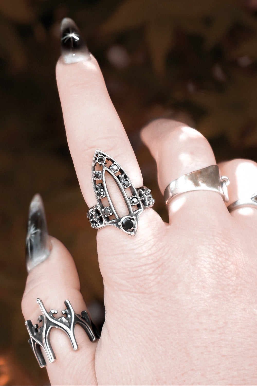 Close-up of a hand wearing multiple silver rings with a blurred background