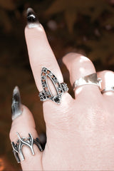 Close-up of a hand wearing multiple silver rings with a blurred background