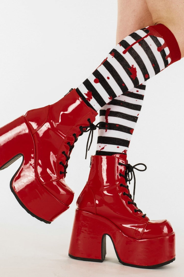 Red platform boots with black and white striped socks featuring red polka dots on a white background