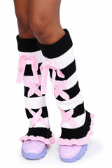 Black and white striped leg warmers with pink bows and ruffles worn by a person on a white background.