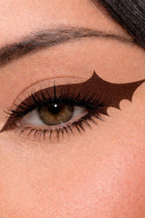 Close-up of a woman's eye with bat-shaped brown eyeliner design.