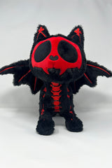 Black and red plush cat toy with bat wings on a white background