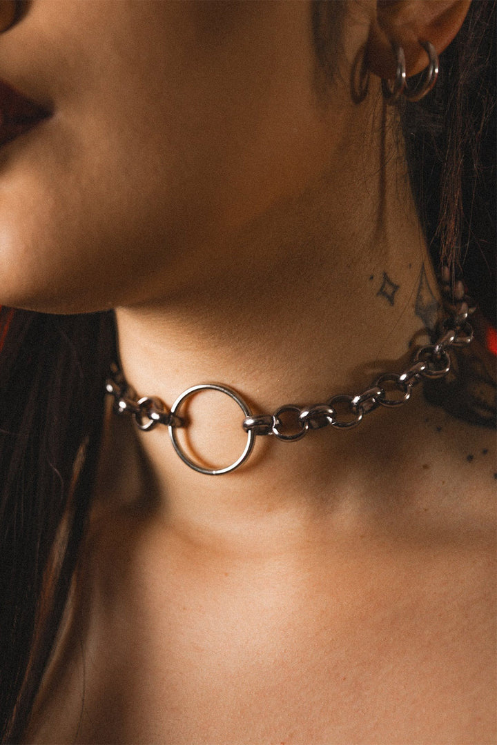 Close-up of a person wearing a chain necklace with an o ring in the middle 
