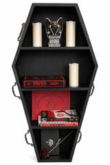 Black coffin-shaped shelf with books, candles, and a figurine on a white background