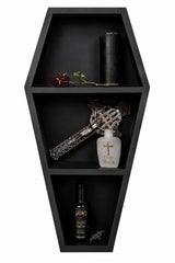 Black coffin-shaped shelf with decorative items including a bottle, cross, and rose.