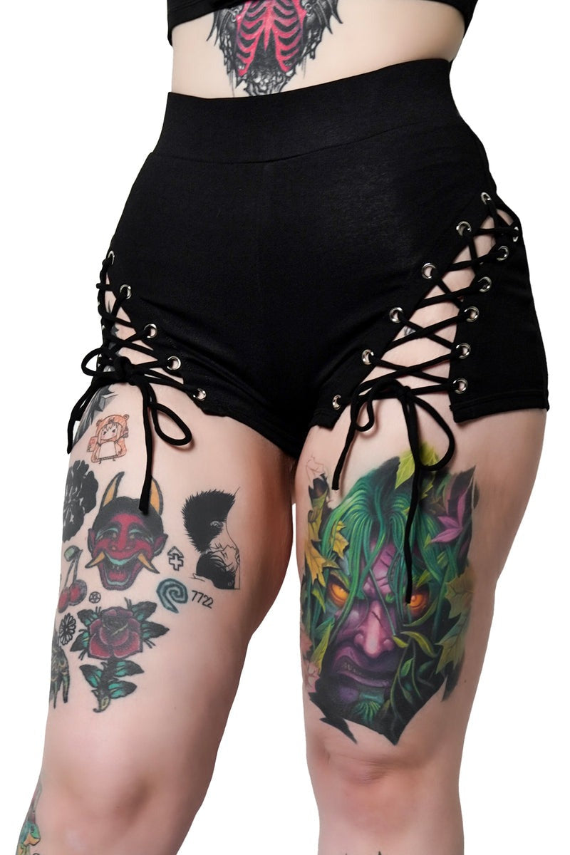 Black lace-up shorts worn by a person with tattoos on a white background