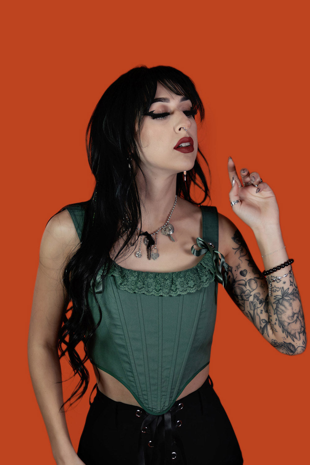 Woman wearing a green corset top against an orange background