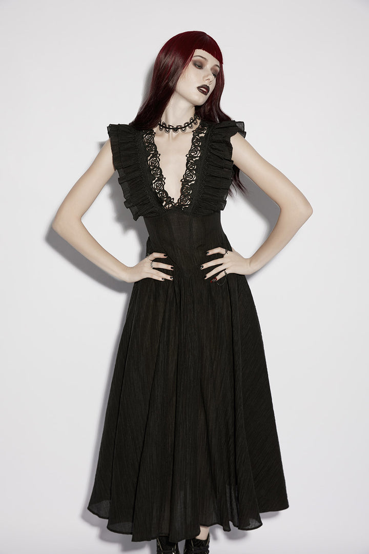 Woman wearing a black dress with ruffled sleeves and lace details on a white background
