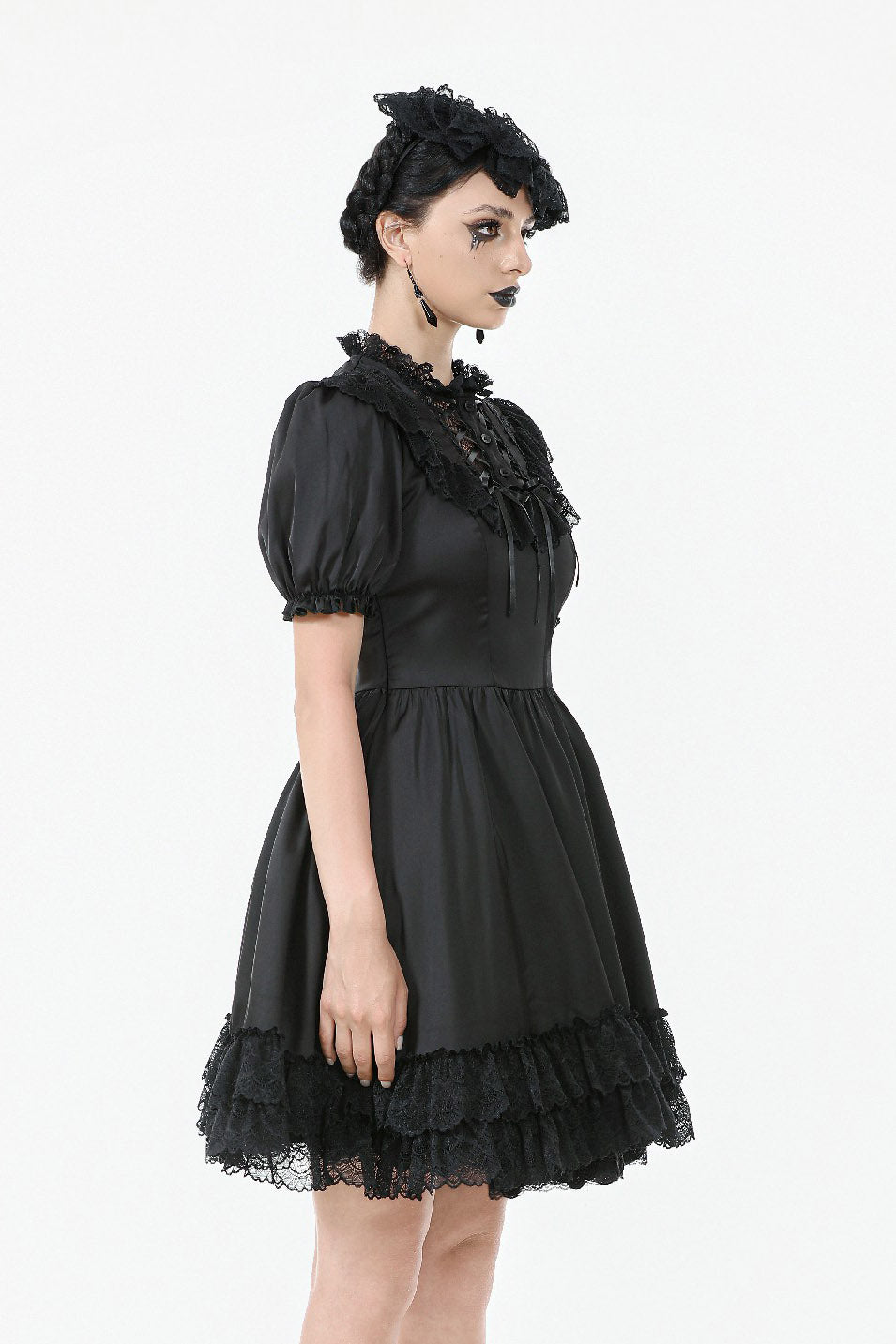 Woman wearing a black gothic-style dress with lace details on a white background
