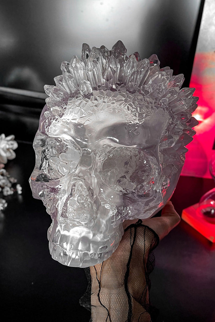 Crystal skull with spiked crystals held by a hand against a blurred background
