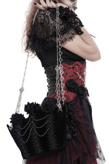 Person wearing a gothic-style outfit with lace sleeves and floral bag 