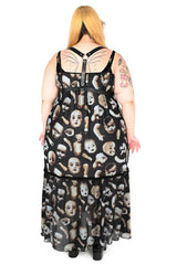 Back view of model wearing a long black dress with broken doll parts on the fabric