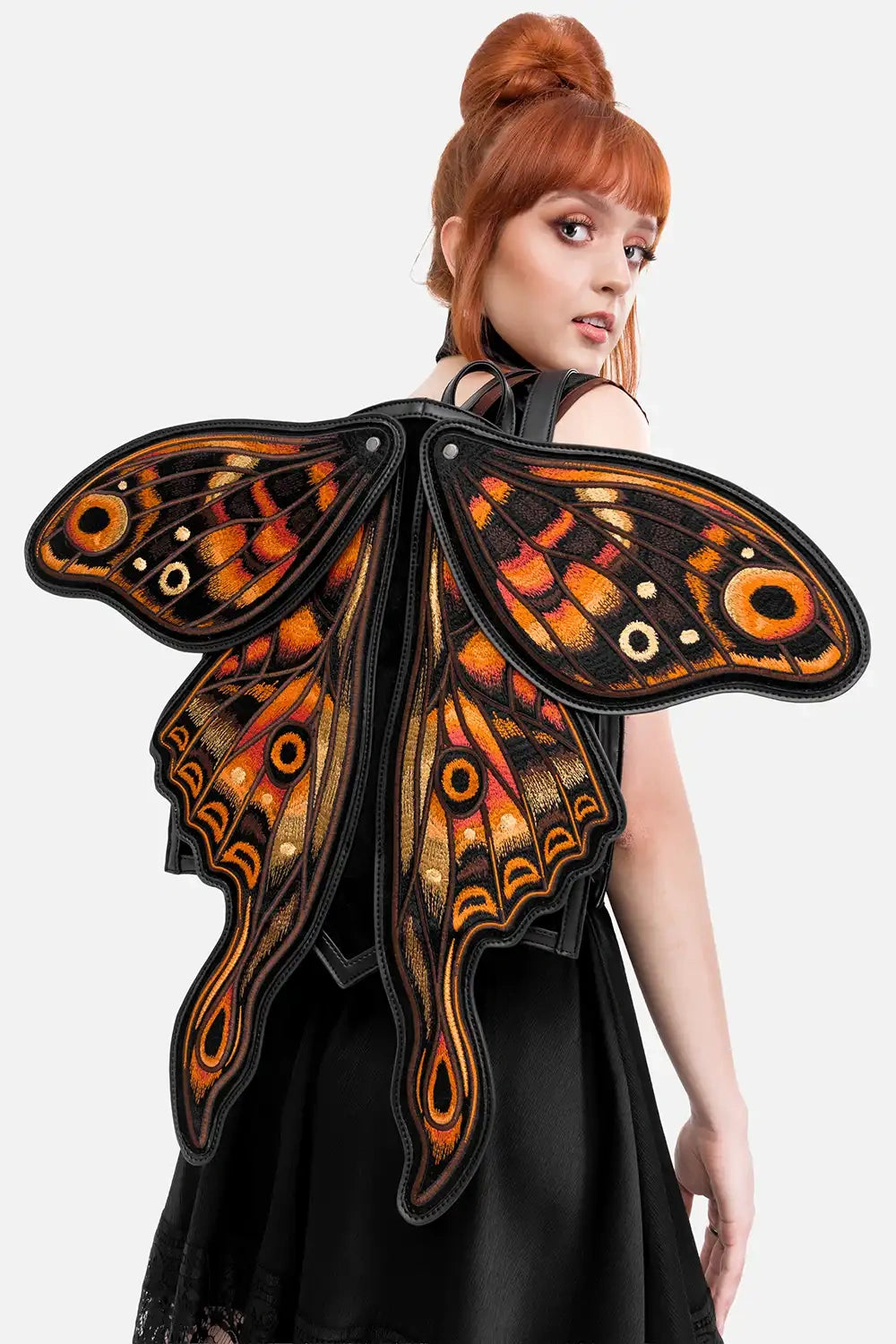 Person wearing butterfly wings backpack with orange and black patterns on a white background