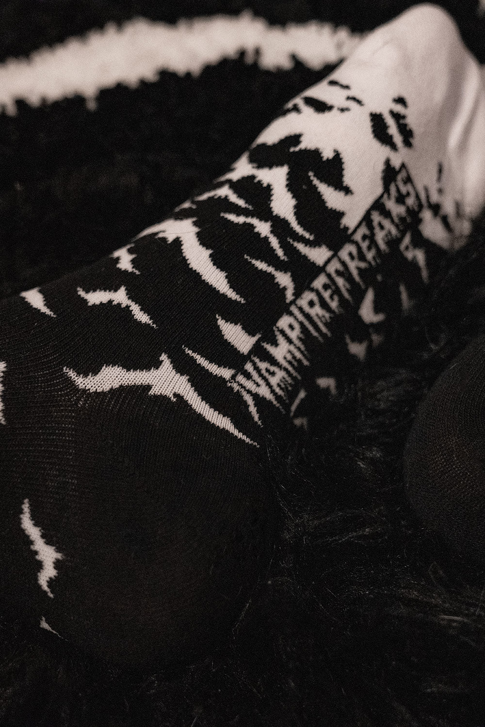 Black and white patterned sock with visible vampire freaks branding on a dark background