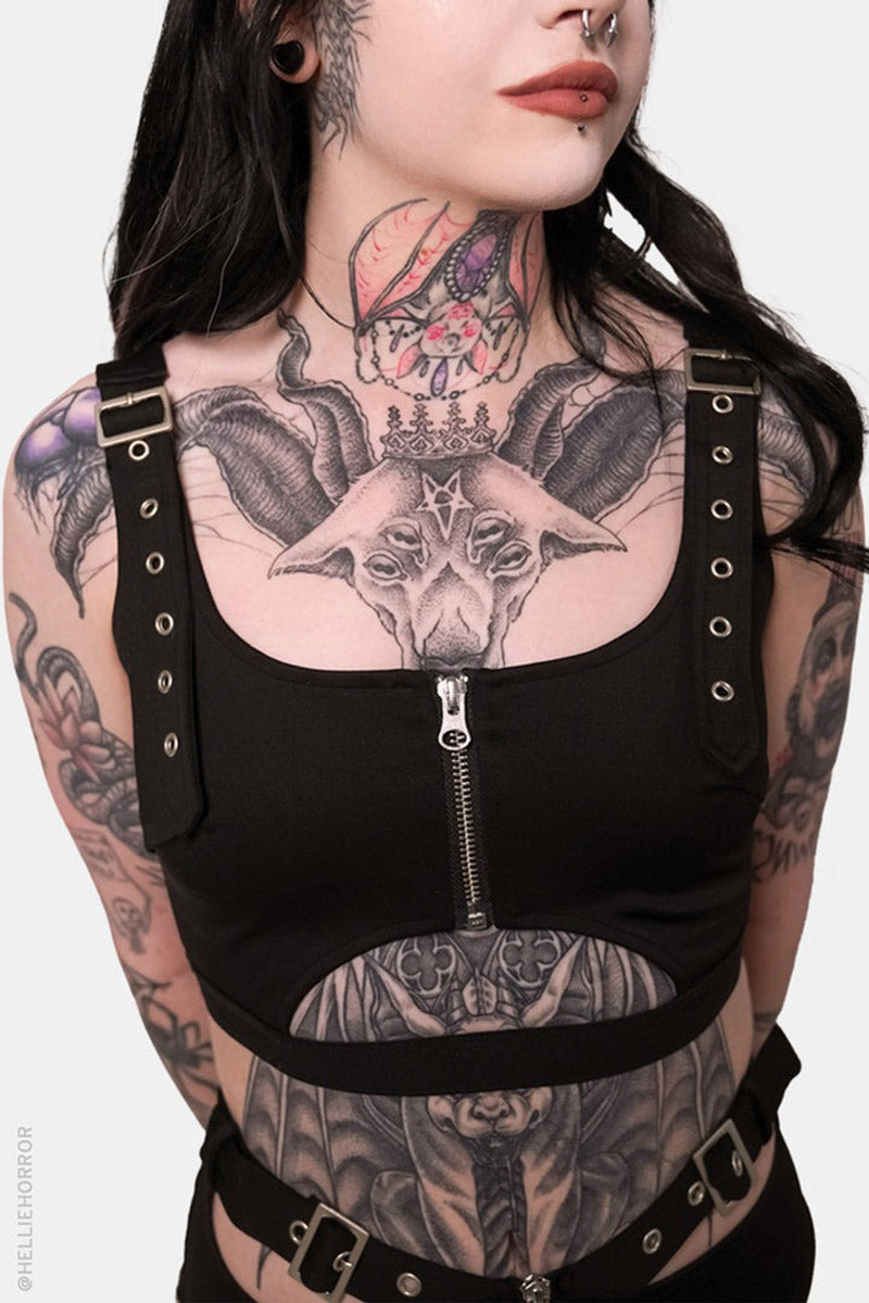 gothic girl  wearing a black harness with visible tattoos on a white background