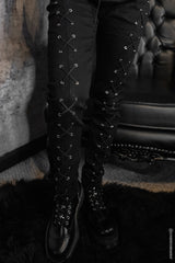 Black lace-up boots worn with womens skinny jean pants against a textured wall.