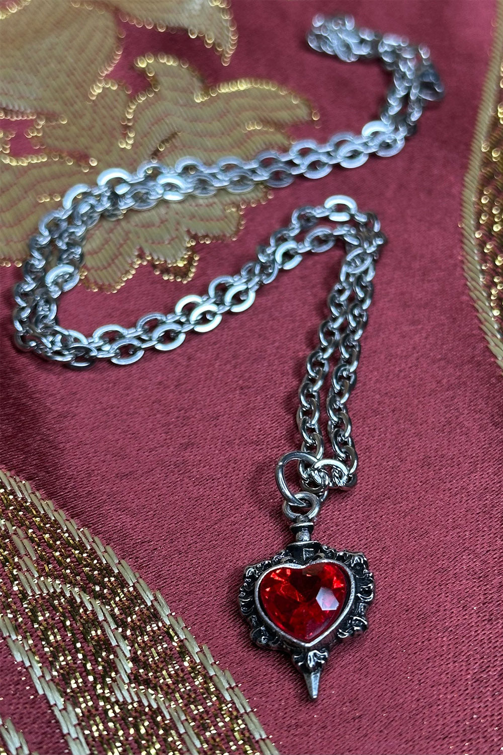 long chain necklace with dagger piercing heart pendant
