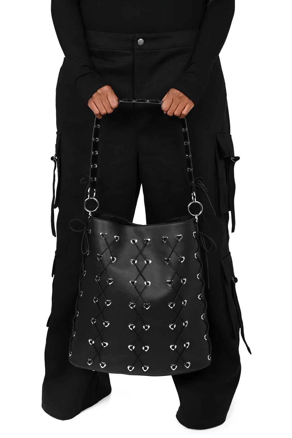 Black studded handbag held by a person wearing black clothing on a white background
