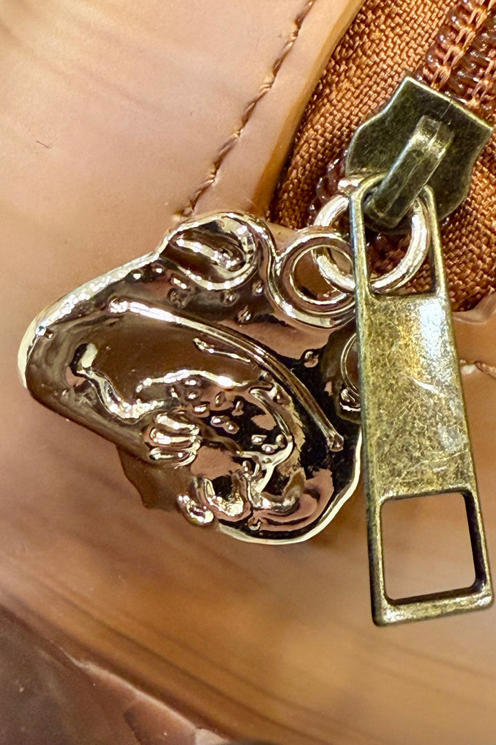 Close-up of a gold zipper pull with a detailed frog design on a snail purse