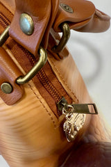 Close-up of a brown snail bag with gold hardware on a neutral background