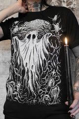 Person wearing a black t-shirt with a white graphic design of a ghostly figure and candles.
