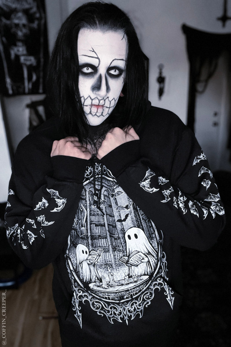 gothic man wearing corpse paint wearing a gothic ghost hoodie of ghosts reading books in a cathedral frame 